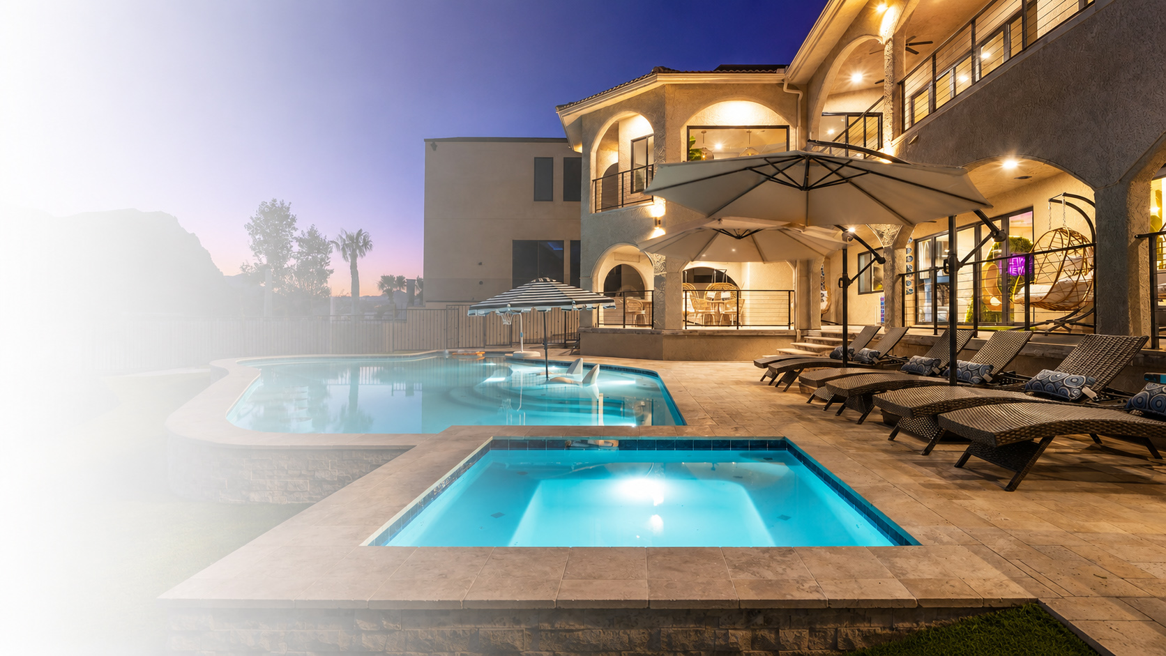 Luxury vacation rental with an illuminated pool at dusk